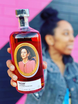 a woman holding up a bottle of whiskey to a close up in in-focus camera shot