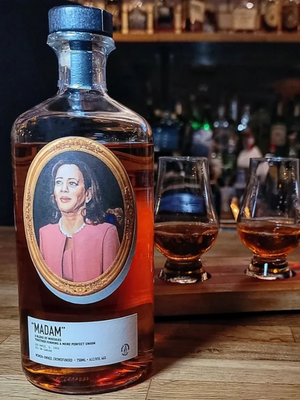 Close up image of a bottle of whiskey on a wooden bar with two poured glasses.